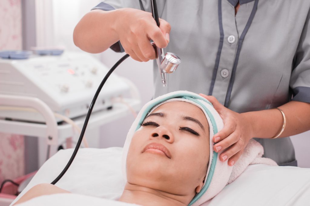 beautician perform beauty treatment on woman face. applying oxygen therapy