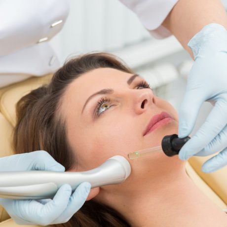 Cosmetic injection to the pretty caucasian woman face and beautician hands with syringe